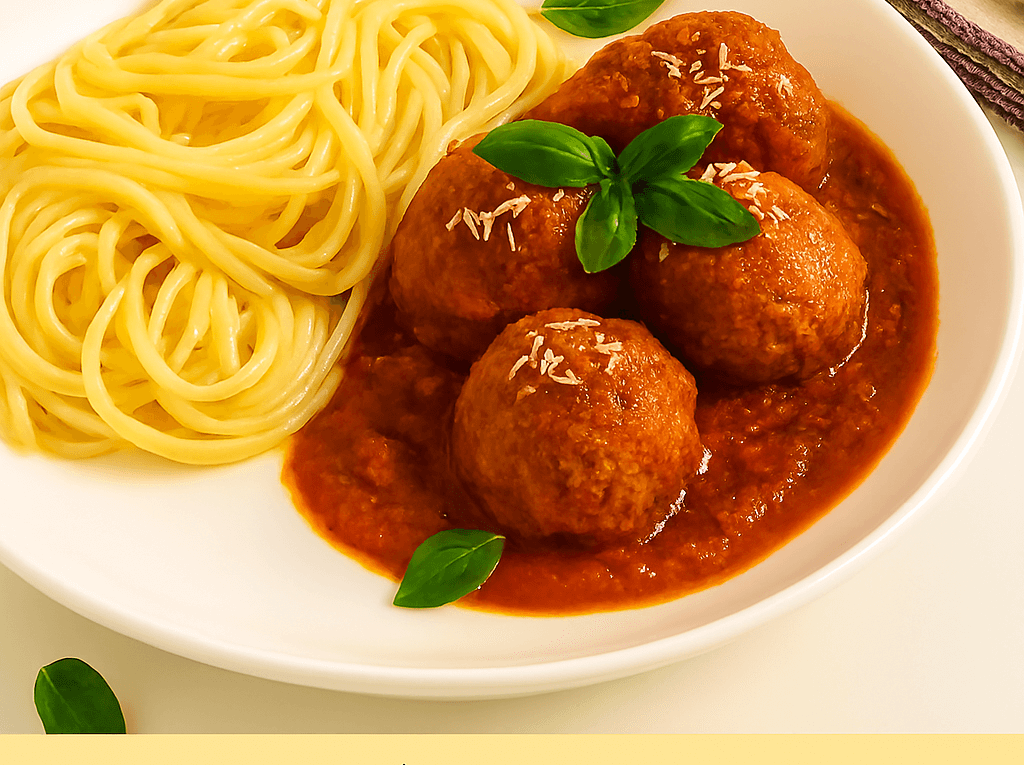 Almôndegas ao sugo caseiras servidas em um prato fundo branco ao lado de espaguete, cobertas com molho de tomate, queijo parmesão ralado e folhas frescas de manjericão.