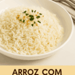 Uma porção de arroz branco soltinho servido em um prato fundo branco, finalizado com pedacinhos de alho frito dourado e cheiro-verde picado.