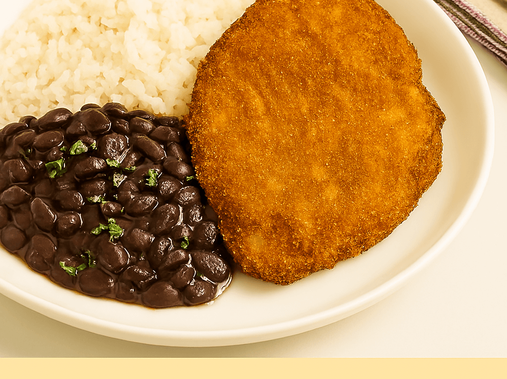 Bife à milanesa sequinho e dourado servido em um prato branco, acompanhado por uma porção de arroz branco e feijão preto salpicado com salsinha.