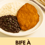 Bife à milanesa sequinho e dourado servido em um prato branco, acompanhado por uma porção de arroz branco e feijão preto salpicado com salsinha.