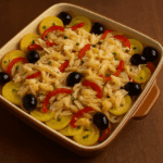 Travessa de vidro borbulhando azeite recém-saída do forno, cheia de lascas de bacalhau suculentas, batatas, pimentões, cebola, azeitonas pretas e ovos cozidos.