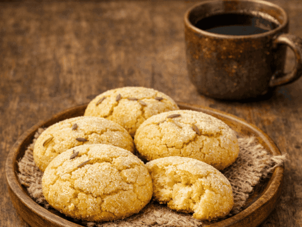 Assadeira contendo várias broas de fubá rústicas, com a superfície levemente dourada e pontilhada por grãos de erva-doce.