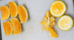 laranja preparada para bolo: fruta lavada, pontas removidas, dividida em quatro partes em formato de meia-lua, sementes retiradas e miolo branco espesso descartado.