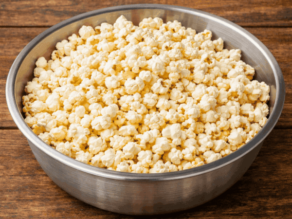 Tigela grande e cheia de pipocas de panela branquinhas e super crocantes, recém-estouradas, regadas com manteiga derretida e prontas para a sessão de cinema em casa.