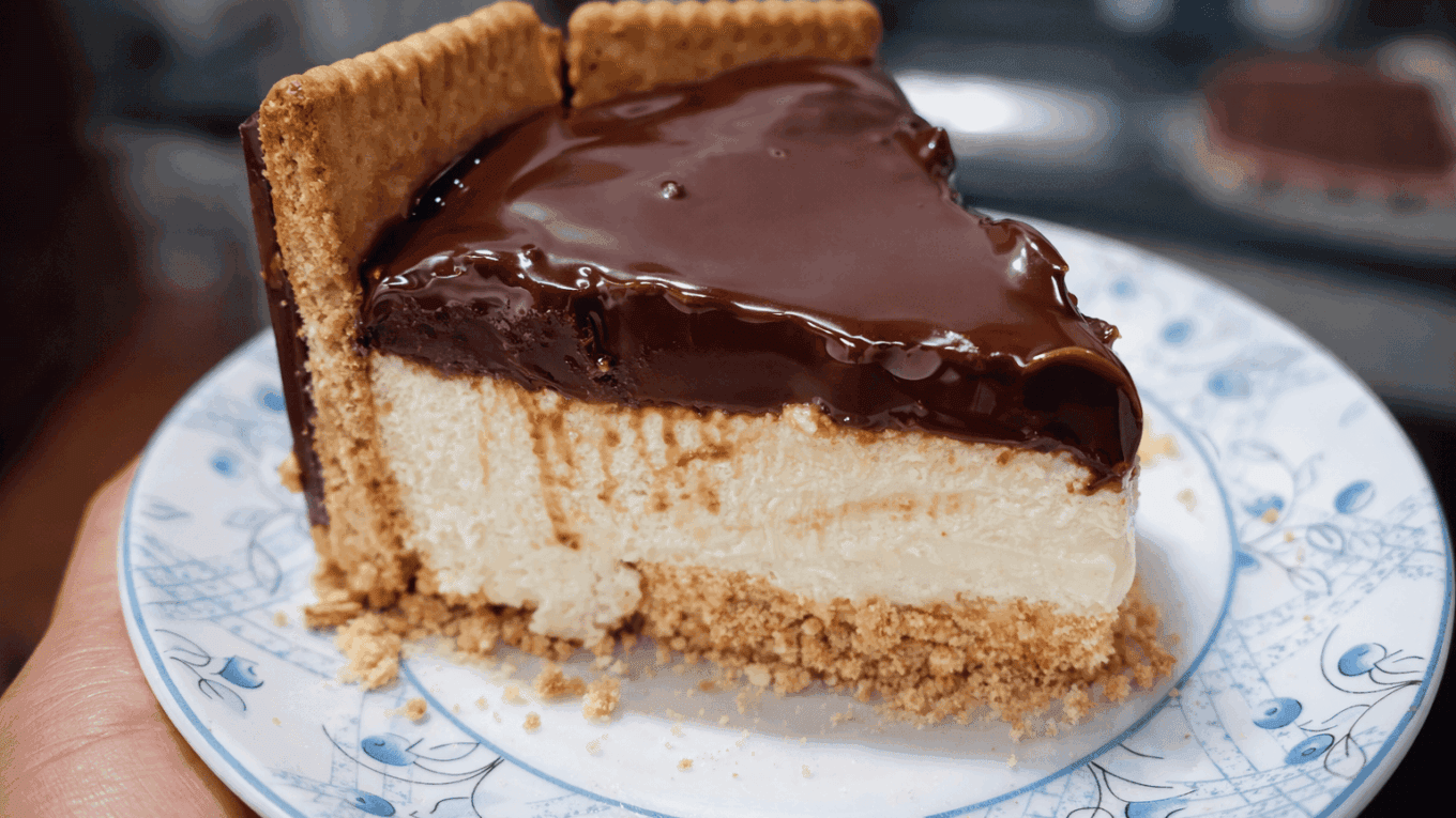Travessa de vidro exibindo as camadas da Torta Holandesa: base crocante de biscoito, creme branco aveludado, cobertura brilhante de ganache de chocolate e laterais decoradas com biscoitos redondos Calipso.