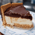 Travessa de vidro exibindo as camadas da Torta Holandesa: base crocante de biscoito, creme branco aveludado, cobertura brilhante de ganache de chocolate e laterais decoradas com biscoitos redondos Calipso.